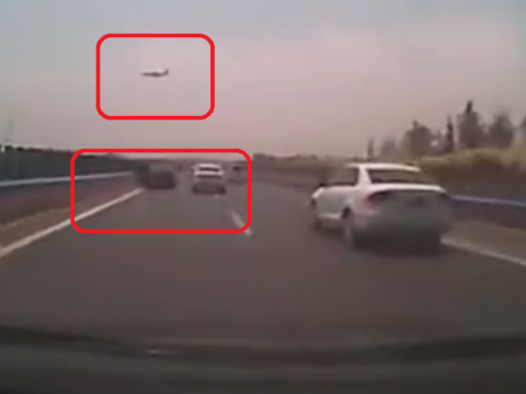 高速道路の上を飛ぶ飛行機と、止まっている故障車