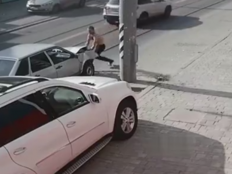 車を叩いて補修しようとする男性