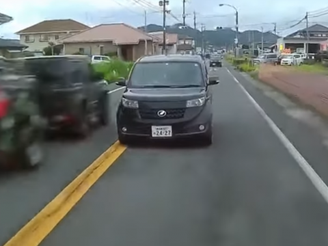 対向車線にはみ出す危険運転をする黒い乗用車