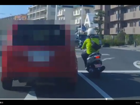 赤い車に接近していくバイク