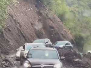 崖が崩れてくる中を通過する車たち